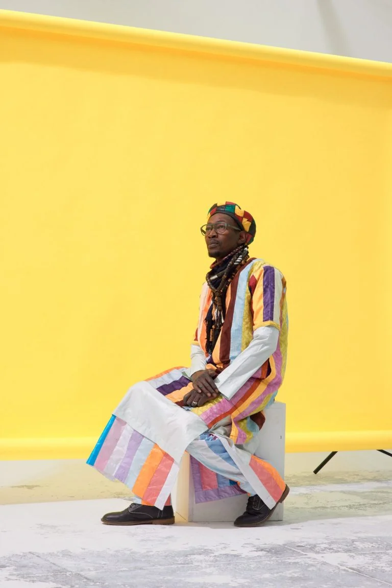 Dans le studio photo Cyclorama Amed, chanteur en tenue traditionnel Sénégalais sur fond papier jaune et sol blanc.
